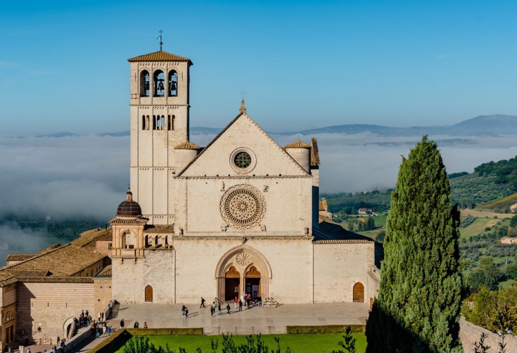 The Basilica of Saint Francis in Assisi, with the green Umbrian valley behind it