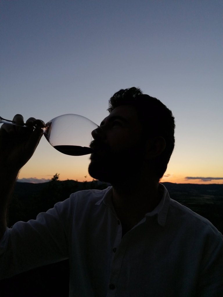 Silhouette of Riccardo drinking red wine at sunset, with the Umbrian hills behind him